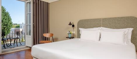 A hotel room with a large bed, a small table with a lamp, a chair, and a view of the outdoors.