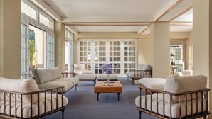 Un salon spacieux avec un plafond haut, de grandes fenêtres et une table basse centrale.