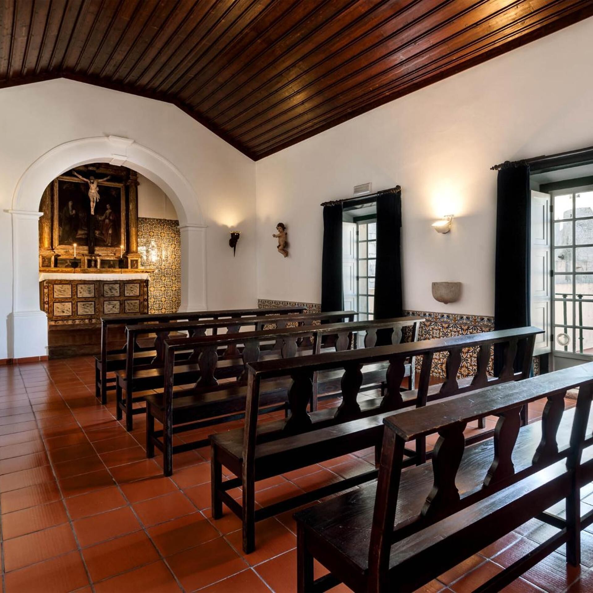 A church interior with wooden pews, a crucifix, and a tiled floor.