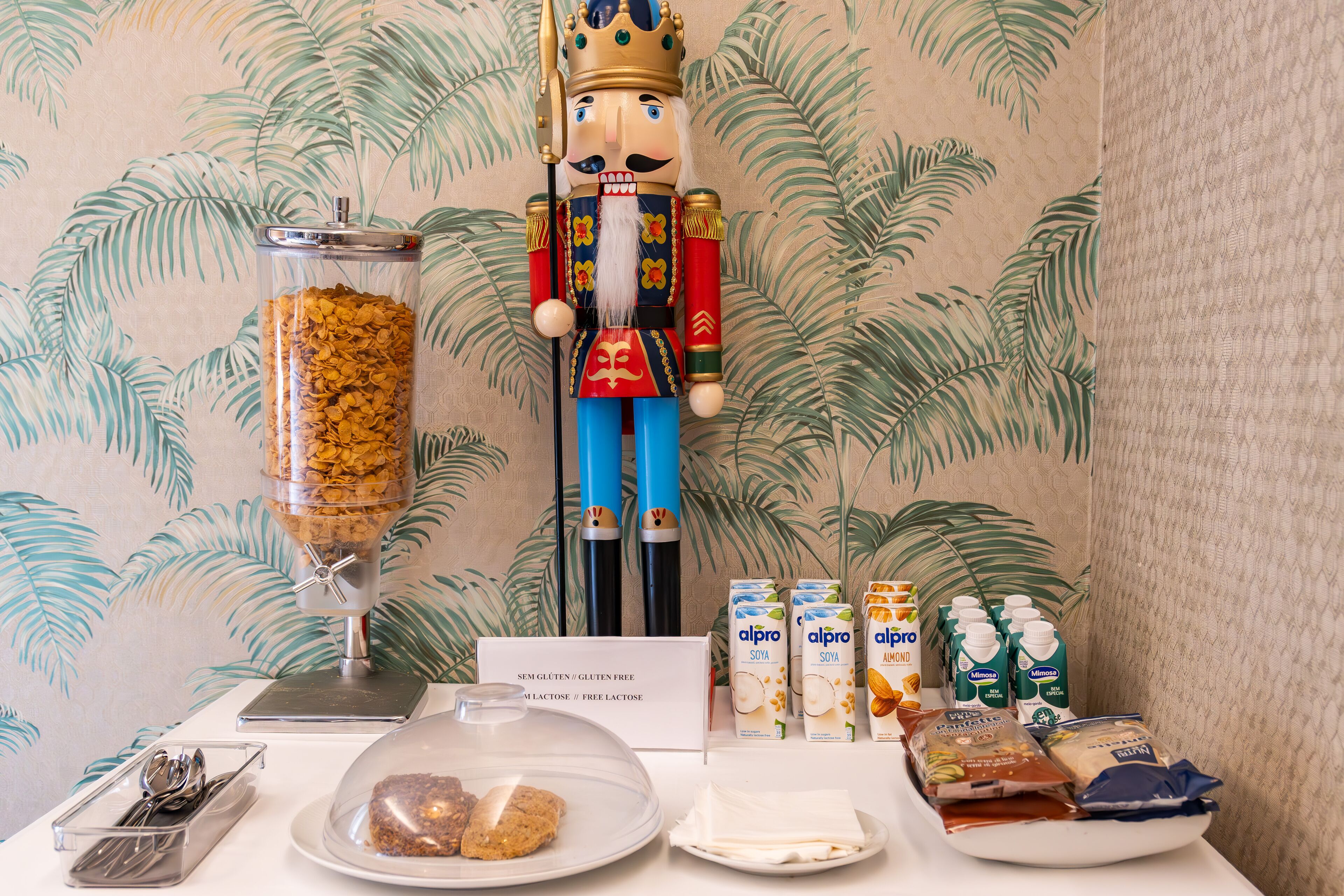 A buffet setup with a nutcracker figure, a cereal dispenser, and various food items including milk cartons and packaged snacks.