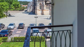 A balcony with a view of a cathedral and parked cars.