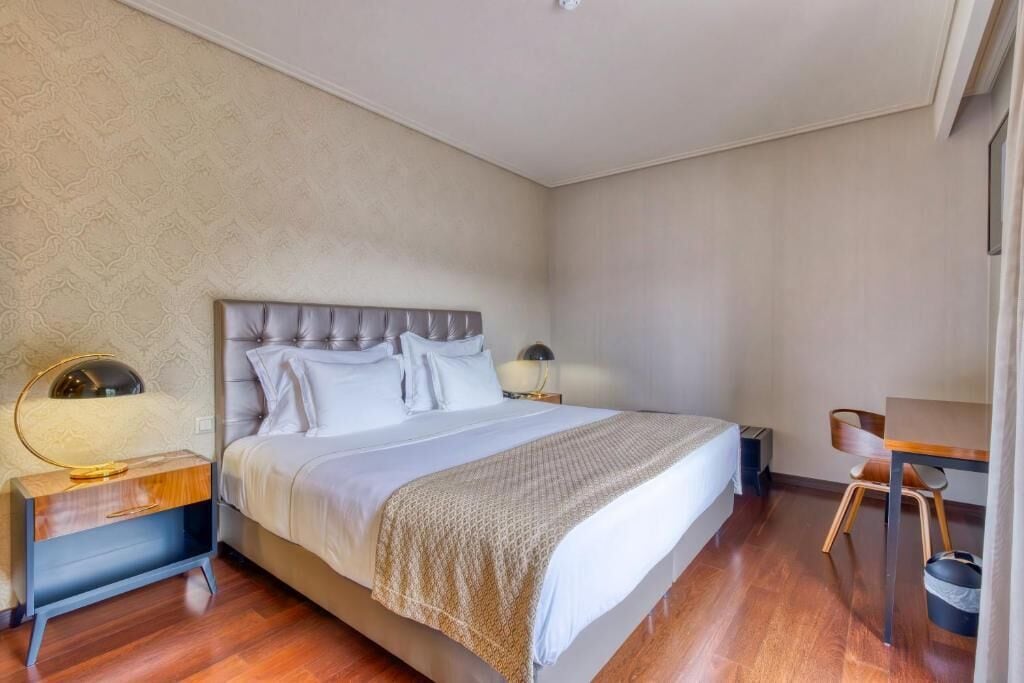 A bedroom with a large bed, bedside tables, a chair, and a desk.