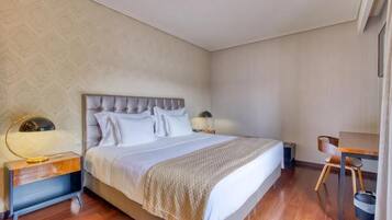 A bedroom with a large bed, bedside tables, a chair, and a desk.