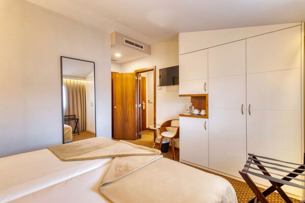 A hotel room with a bed, a chair, a wardrobe, and a television. - Hotel Lis Batalha (Batalha)