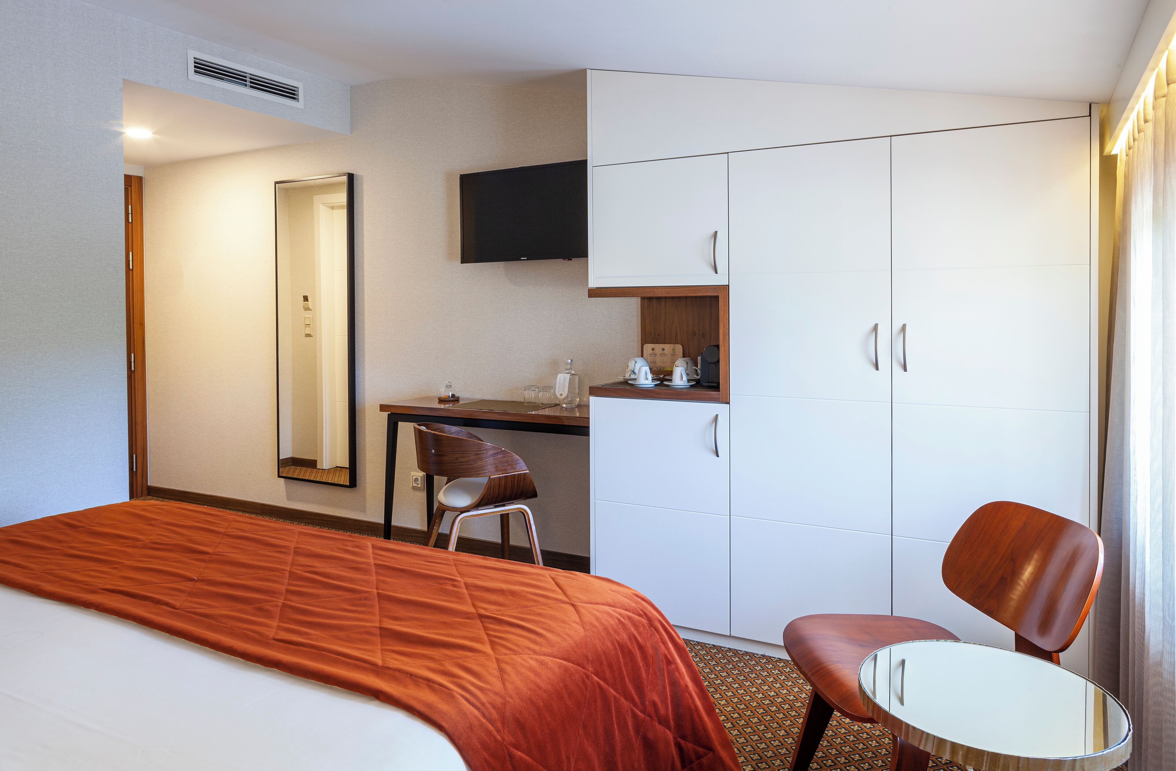 Habitación de hotel con cama, escritorio, silla, televisor y armario.