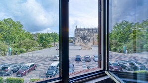 A view from a window of a parking lot with cars and a historic building in the background. - Hotel Lis Batalha (Batalha)