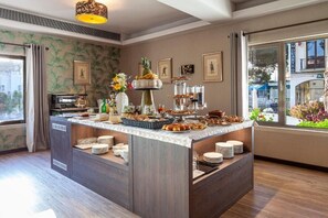 A buffet setup with various food items, a coffee machine, and a decorative vase. - Hotel Lis Batalha (Batalha)