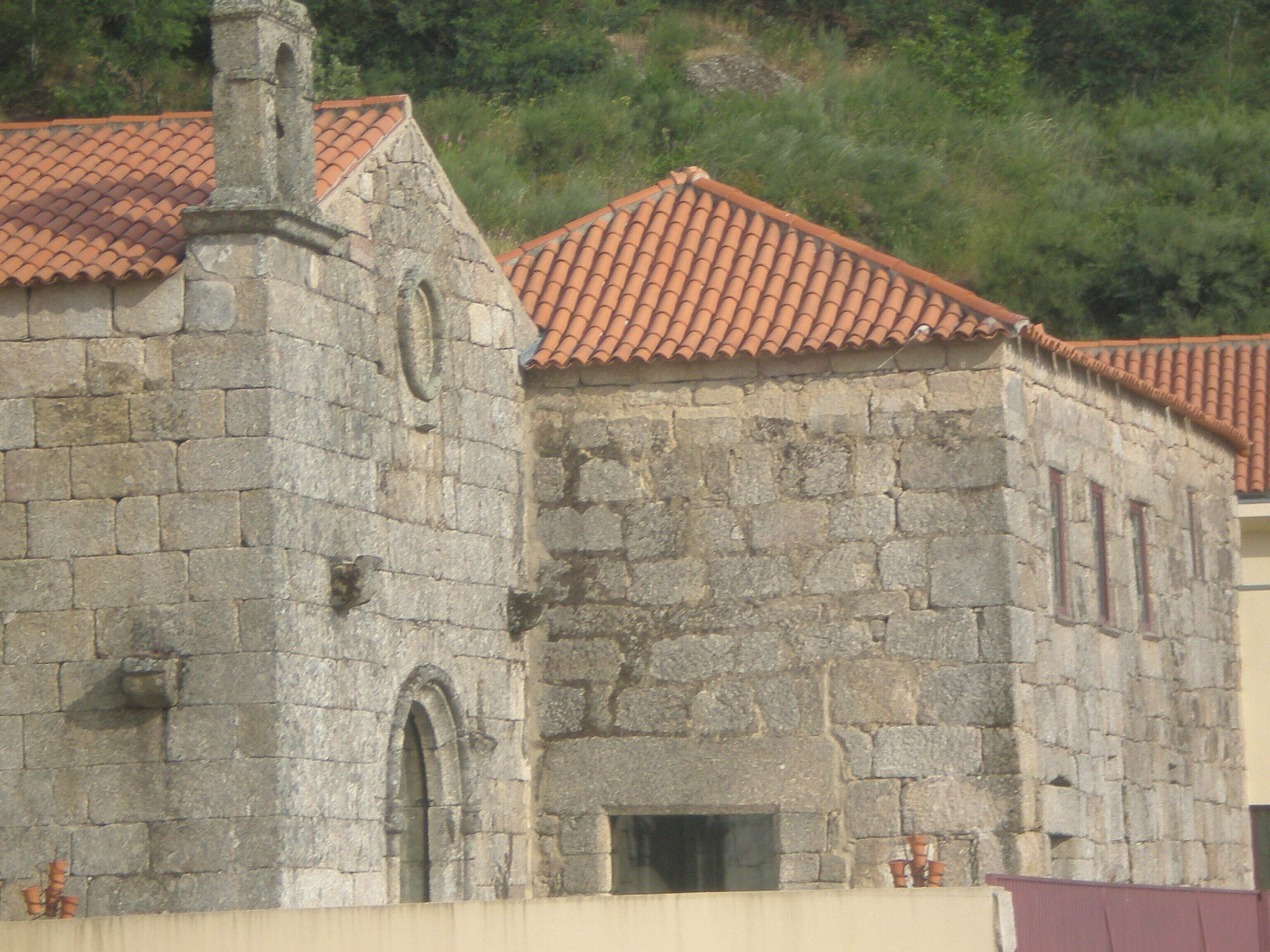 A stone building with a tiled roof and arched windows.