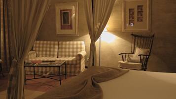 A bedroom with a bed, a checkered sofa, a chair, a small table, and curtains.