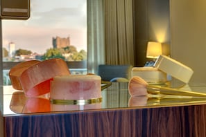 A hotel room with a glass table displaying makeup items and a reflection of a cityscape in the window. - Pousada de Bragança - São Bartolomeu (Braganca)