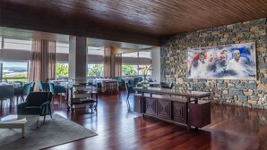 A spacious dining area with high ceilings, a stone wall, and a large painting. - Pousada de Bragança - São Bartolomeu (Braganca)