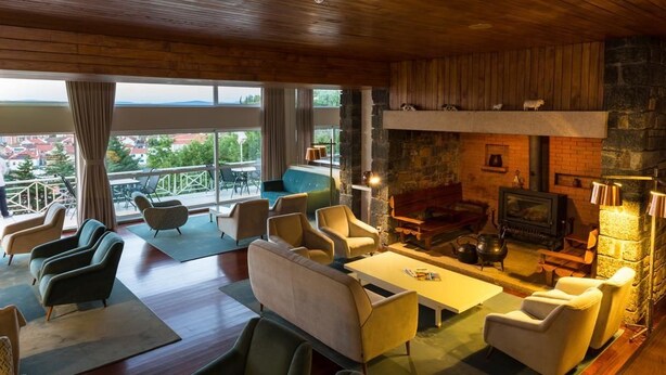 A cozy living room with a fireplace, comfortable seating, and a balcony with a view. - Pousada de Bragança - São Bartolomeu (Braganca)