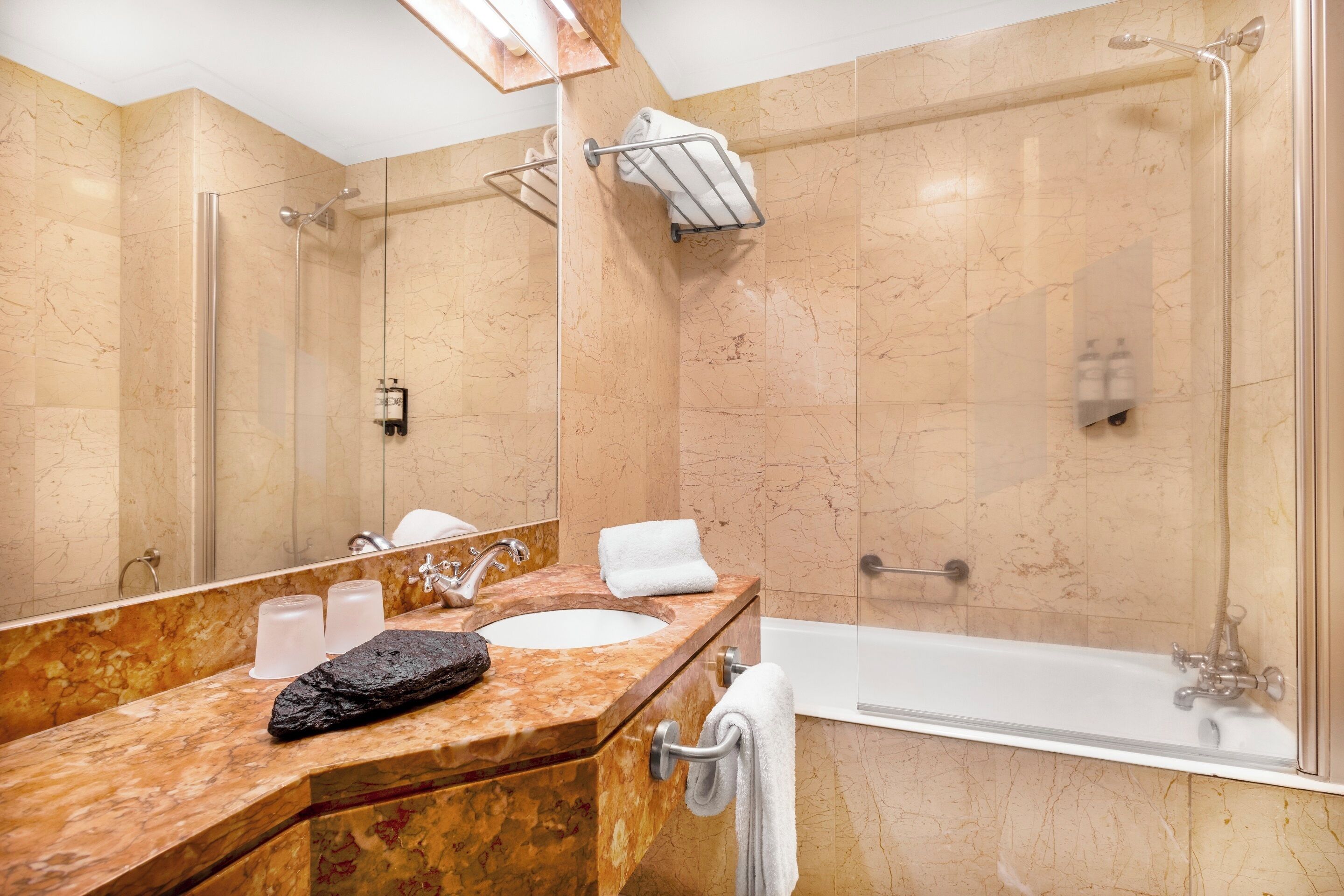 Une salle de bain avec un meuble-lavabo en marbre, une baignoire et une douche à parois de verre.