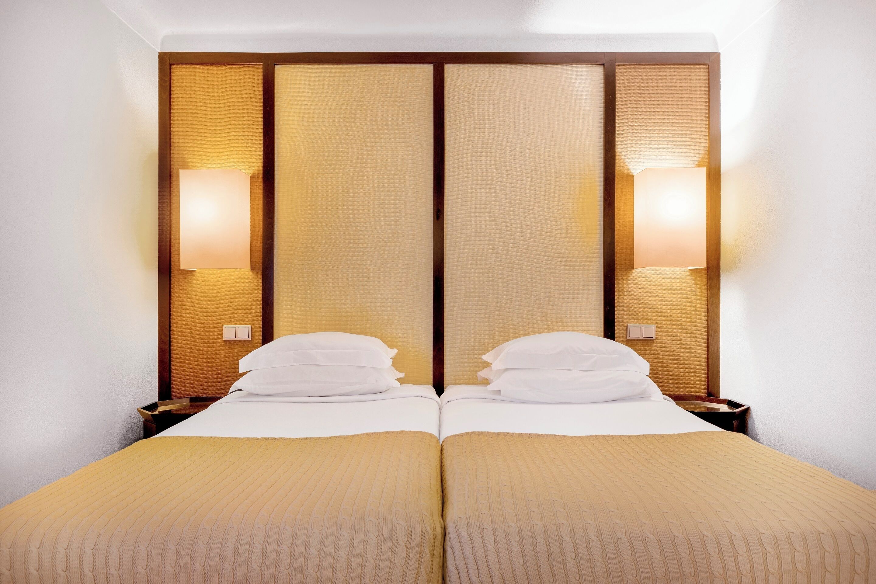 Una cama doble con cabecera de madera y dos lámparas de noche.