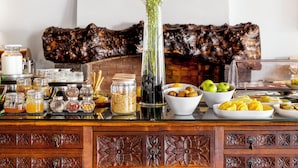 A buffet setup with various food items, a vase with flowers, and a decorative wooden backdrop. - Pousada Forte Horta (Horta)