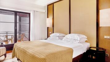 A hotel room with a bed, a nightstand, a chair, and a view of the outside balcony.