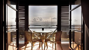 An open balcony with a table and chairs, a view of the sea, and a ship in the distance. - Pousada Forte Horta (Horta)