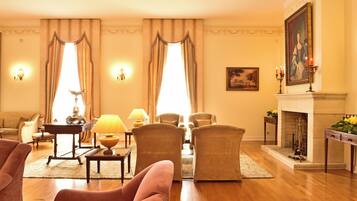 A well-lit living room with a fireplace, comfortable seating, and decorative wall sconces.
