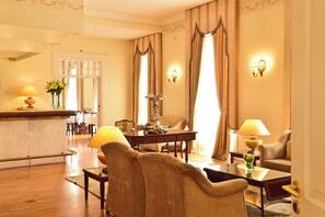 A hotel room with a dining area, a sofa, a table with a vase, and a lamp. - Pousada Queluz (Sintra)