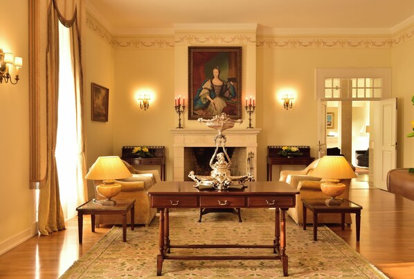 A formal room with a fireplace, a table, and two lamps. - Pousada Queluz (Sintra)
