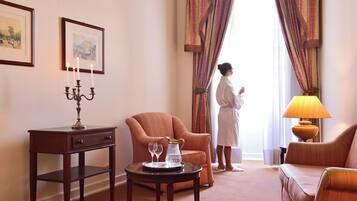 Une chambre d’hôtel avec un coin salon, une table avec une bougie, une lampe et une vue sur l’extérieur.