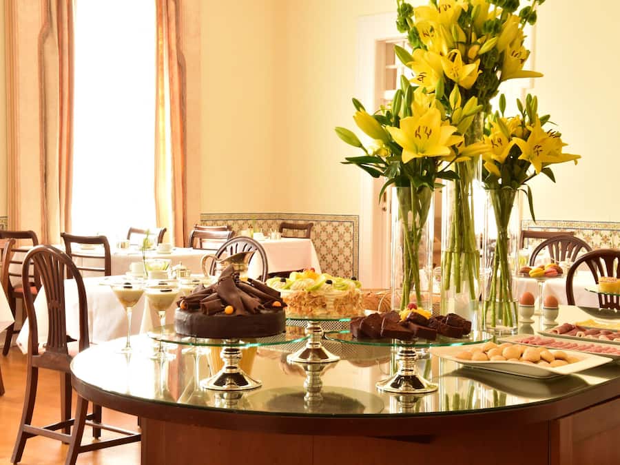 A buffet table with various food items and a vase of yellow flowers.