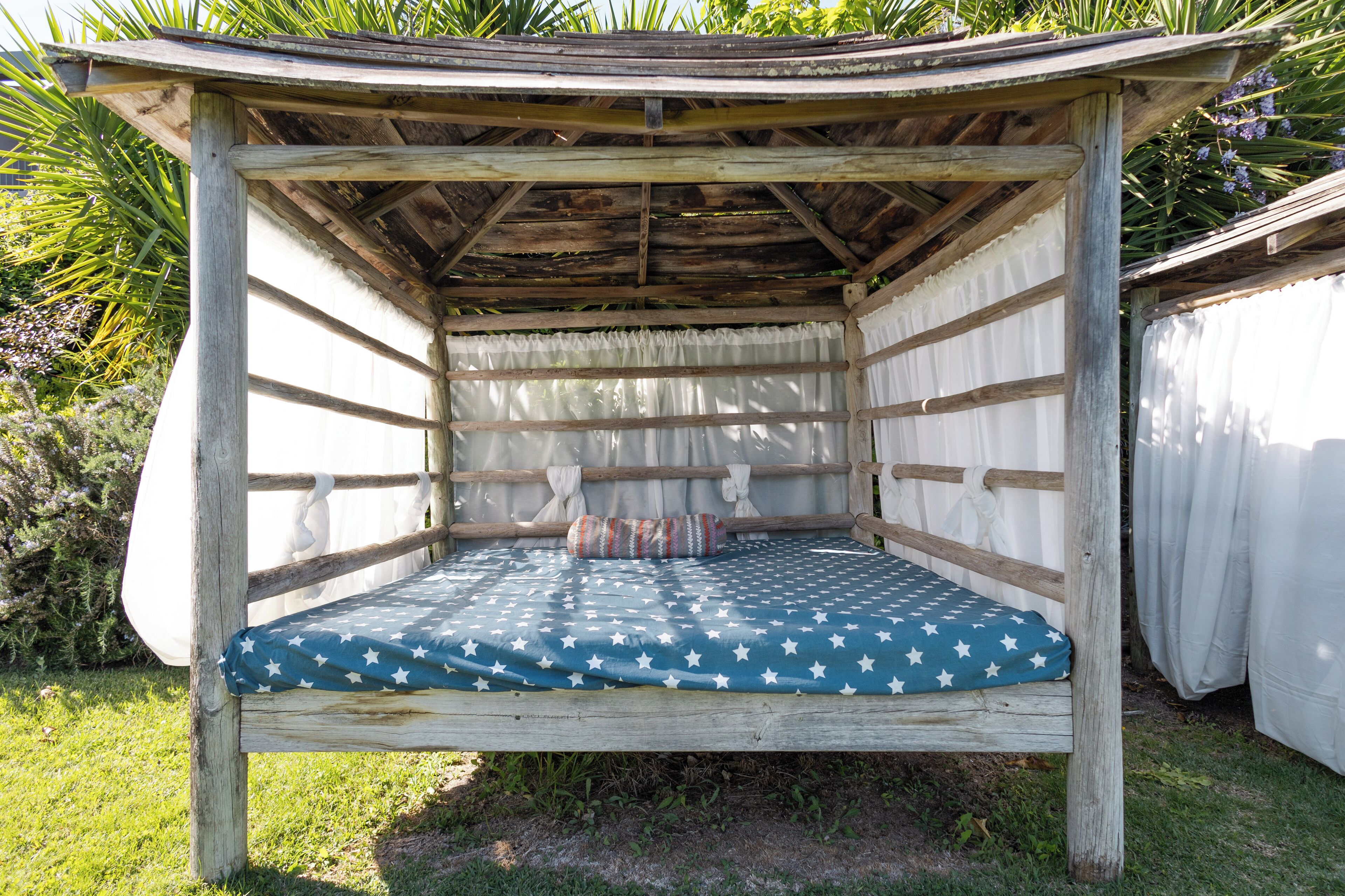 Una cama de madera con un colchón estampado con estrellas, una cortina blanca y un cabecero de madera.