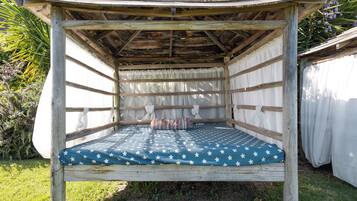 Una cama de madera con un colchón estampado con estrellas, una cortina blanca y un cabecero de madera.