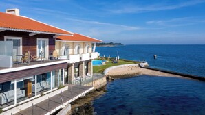 A coastal property with a swimming pool, outdoor seating, and a view of the sea.