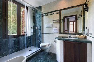 A modern bathroom with a glass-enclosed shower, a toilet, and a vanity with a marble countertop.