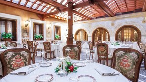 Un comedor con mesas redondas, sillas y un techo alto de vidrio.