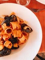 A plate of pasta with mussels on a white plate.