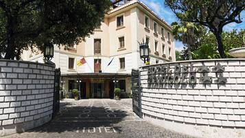 Una entrada de hotel con fachada de ladrillo, un letrero que dice “HOTEL” y una bandera.