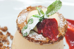A dessert with a berry topping and powdered sugar, served on a plate.