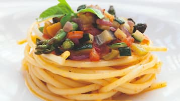 A plate of spaghetti with a colorful vegetable topping.