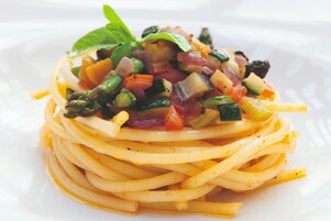 A plate of spaghetti with a colorful vegetable topping.