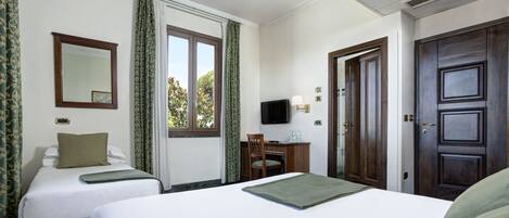 Habitación de hotel con dos camas, un escritorio, una silla, un televisor y una puerta.
