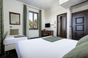 A hotel room with two beds, a desk, a chair, a television, and a door.
