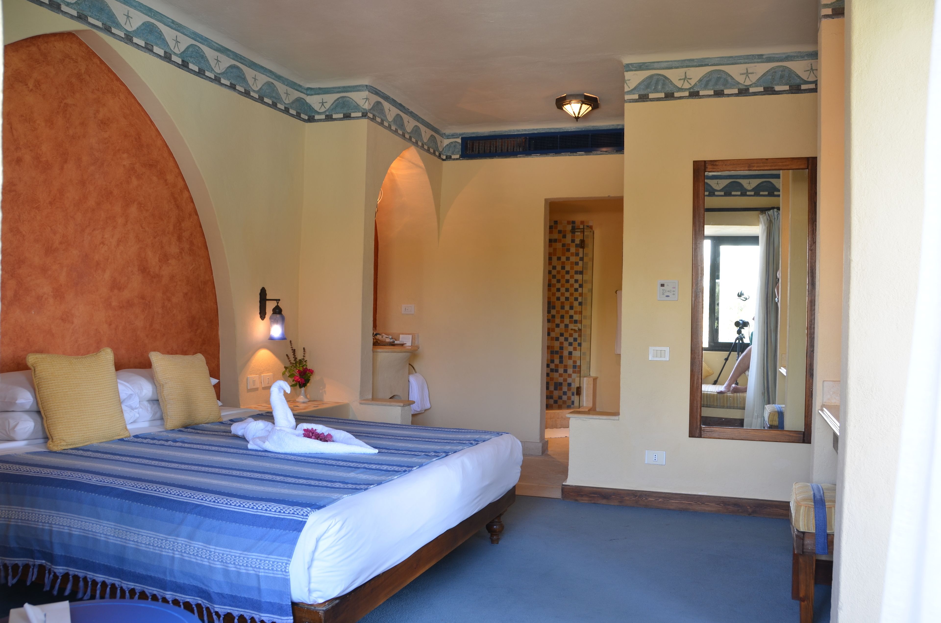 A hotel room with a large bed, a vanity with a mirror, and a small bathroom.