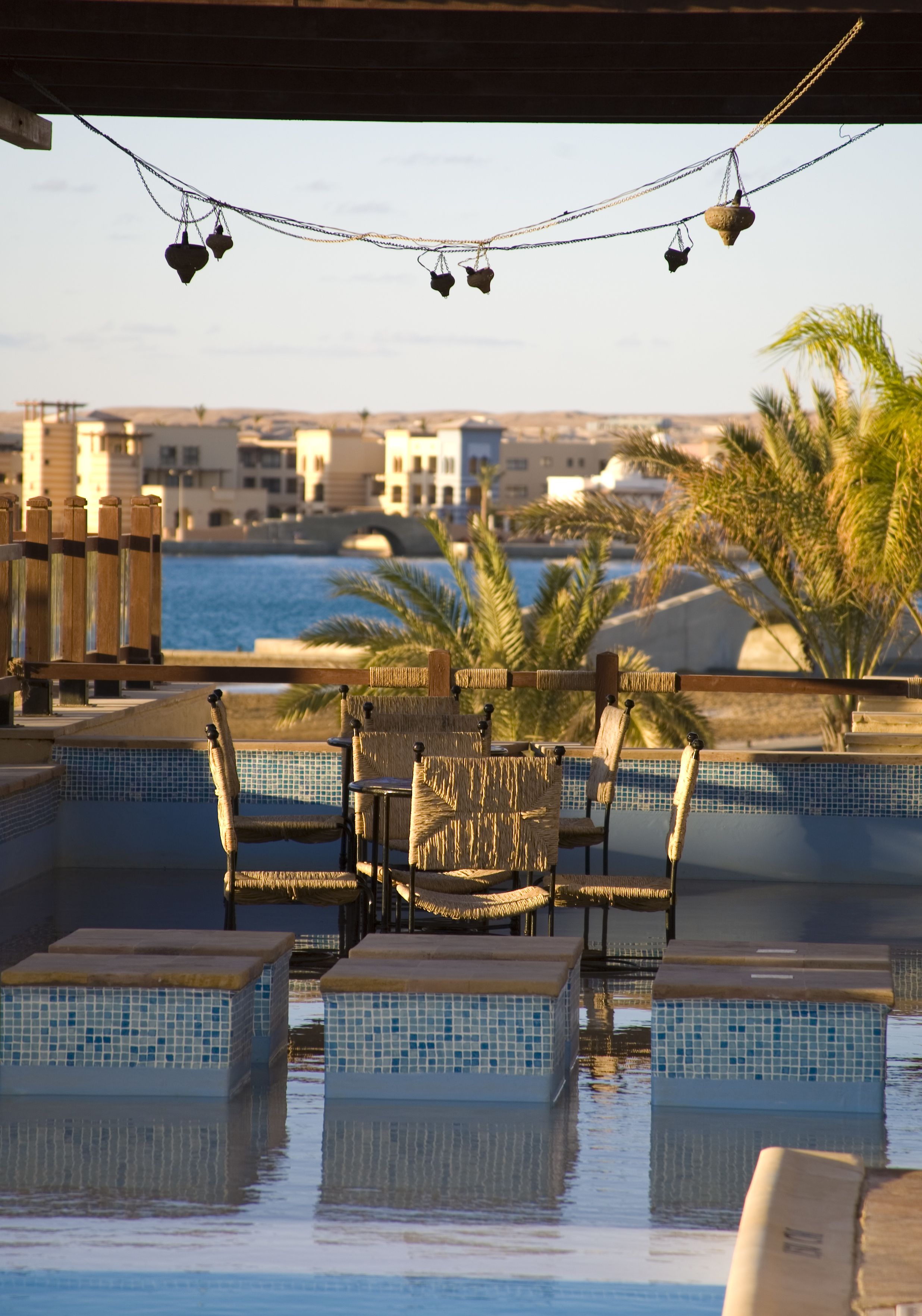 An outdoor pool area with wicker furniture and a view of the sea.