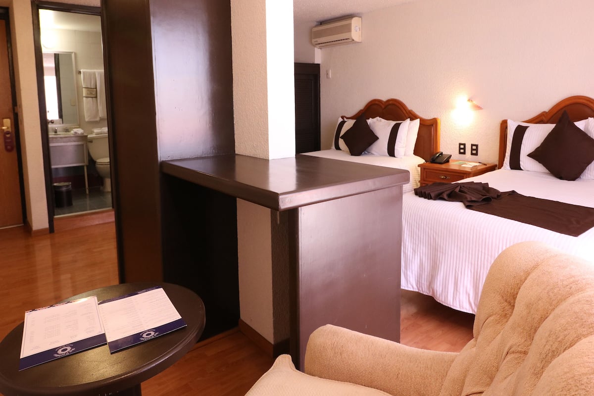 A hotel room with a bed, bedside table, and a desk.