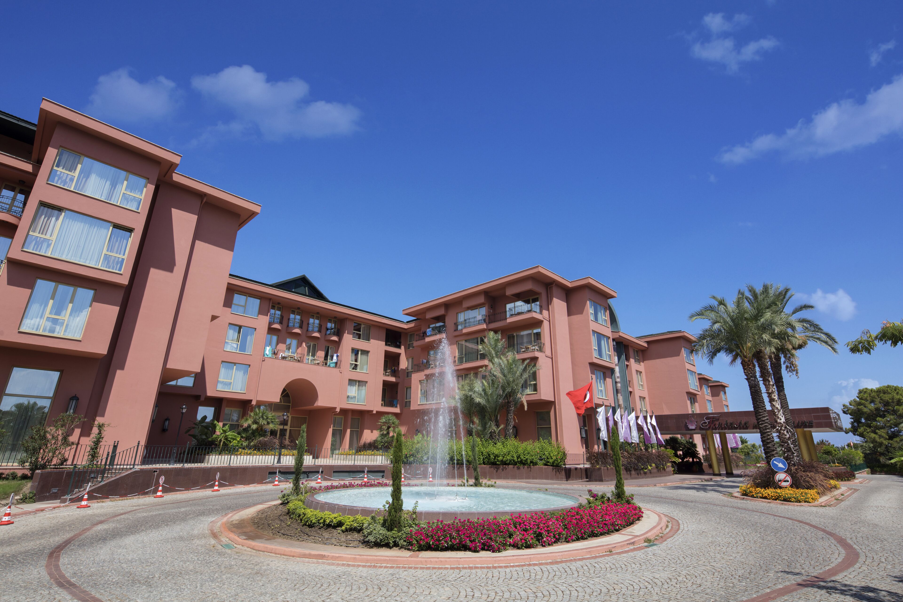 A hotel with a central fountain, multiple balconies, and a clear blue sky.
