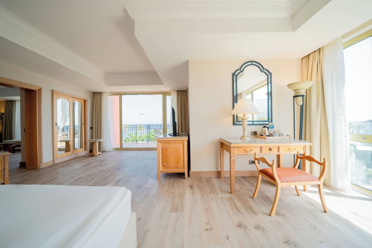 Habitación de hotel con una cama grande, un escritorio de madera con silla, un espejo y vistas al exterior.