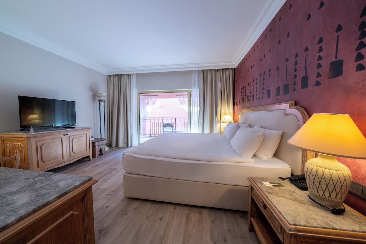 Una habitación de hotel con una cama, un televisor, un escritorio y una lámpara.
