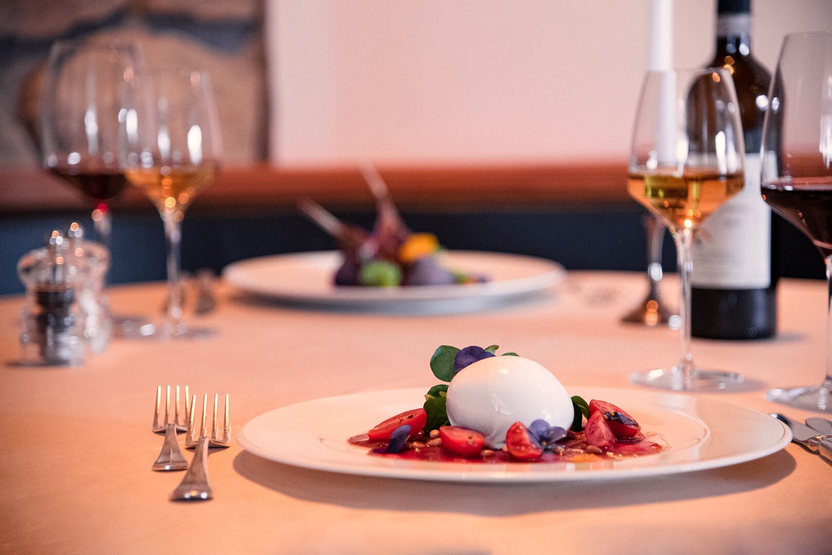 Una mesa de comedor con un plato de postre, copas de vino y una botella de vino.