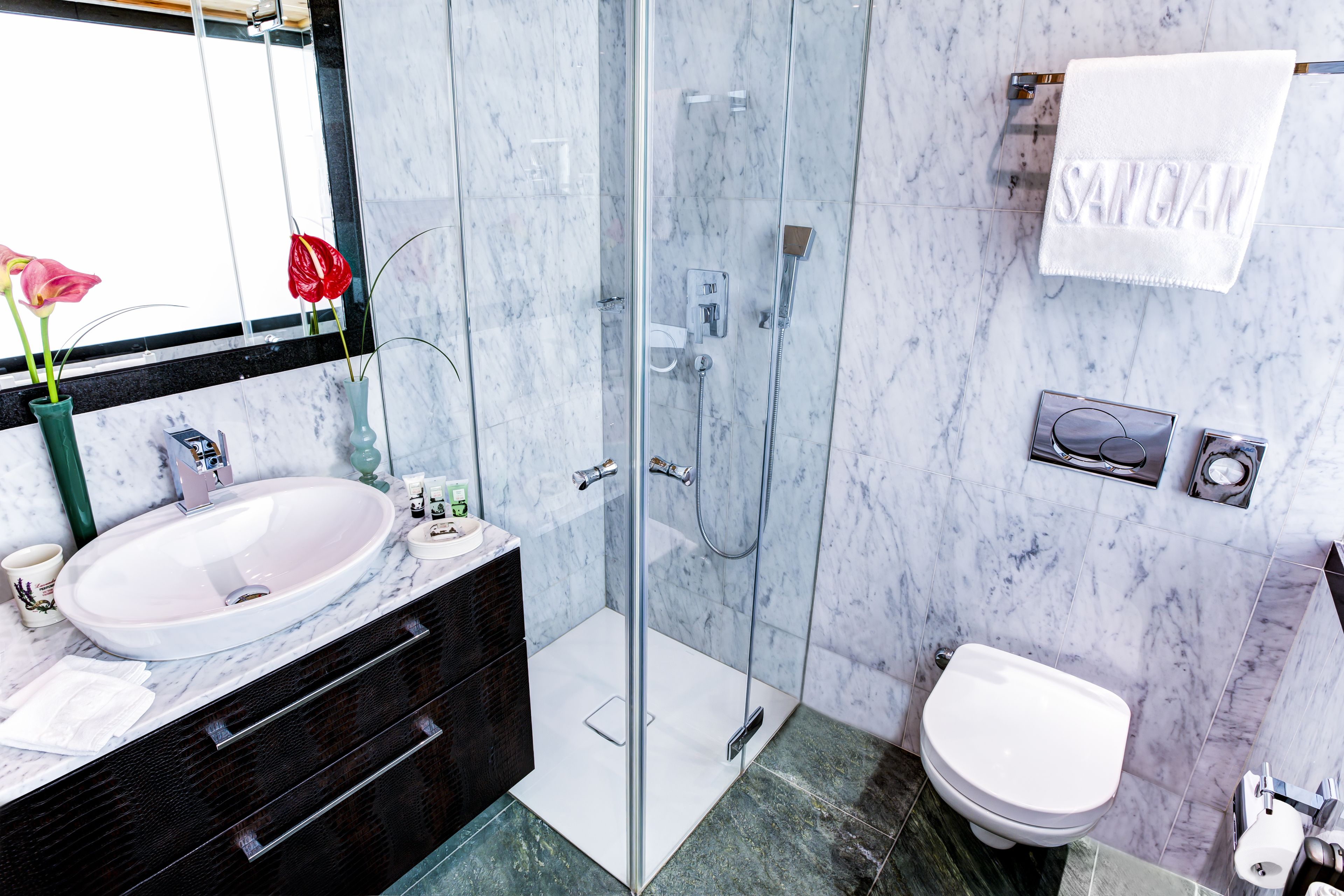 A modern bathroom with a glass-enclosed shower, a white sink, and a toilet.