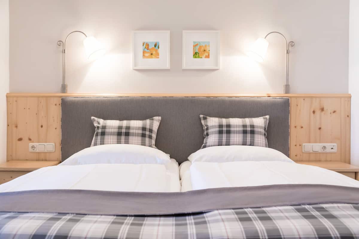 A double bed with a gray headboard, two bedside lamps, and two framed artworks on the wall.
