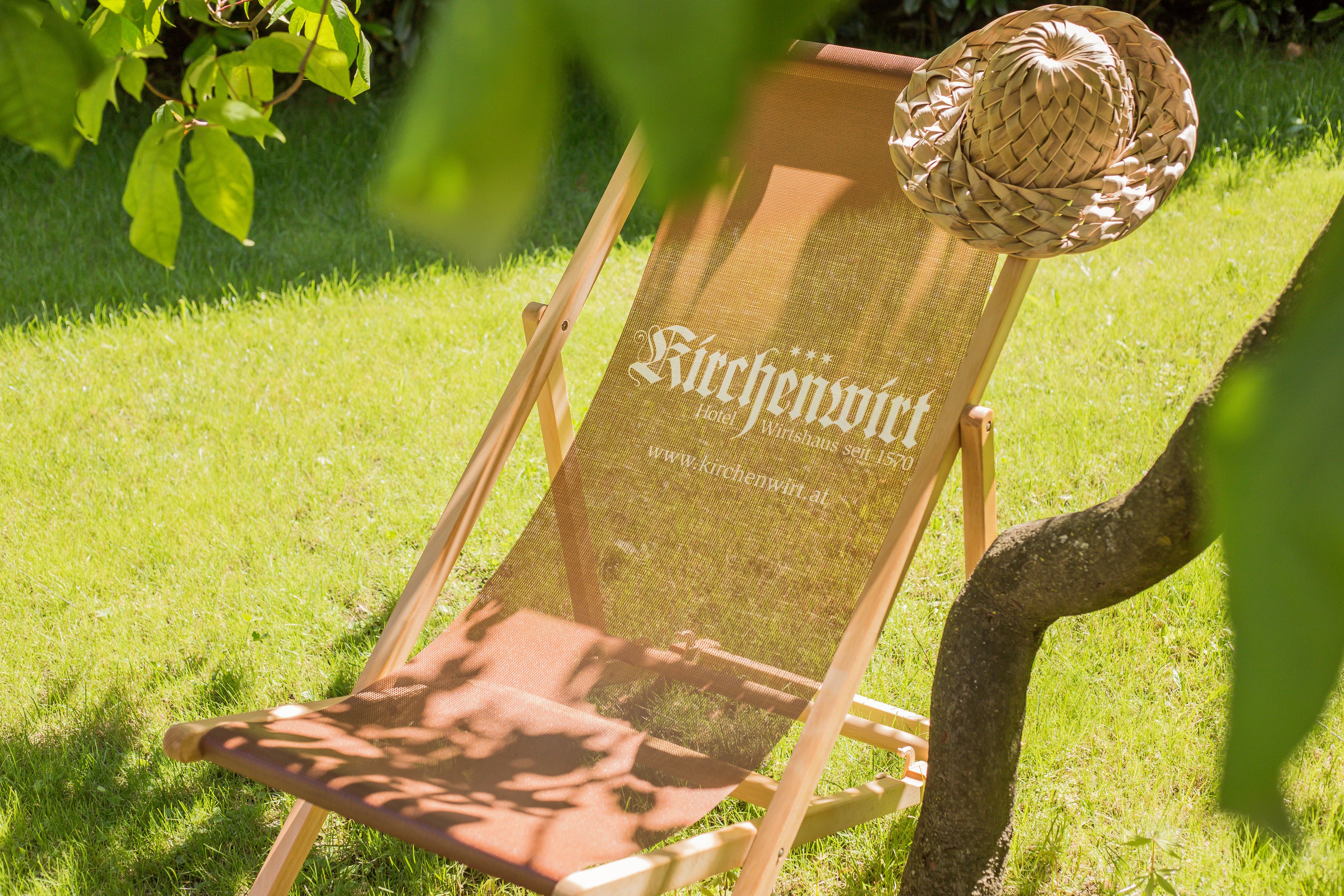 Una silla con un sombrero tejido y un letrero que dice "Kirchenwirt Hotel Wirtshaus 15/16".