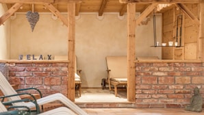 A wooden structure with a brick wall, two chairs, a hanging heart-shaped decoration, and a shelf with two cups. - Hotel Gasthof zum Kirchenwirt (Puch bei Hallein)