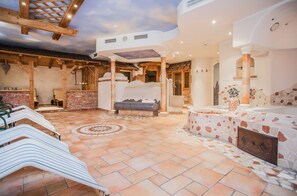A spa area with a stone floor, wooden beams, and a seating area with a massage table. - Hotel Gasthof zum Kirchenwirt (Puch bei Hallein)